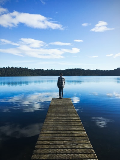 男人站在湖码头下观察水蓝天白天
